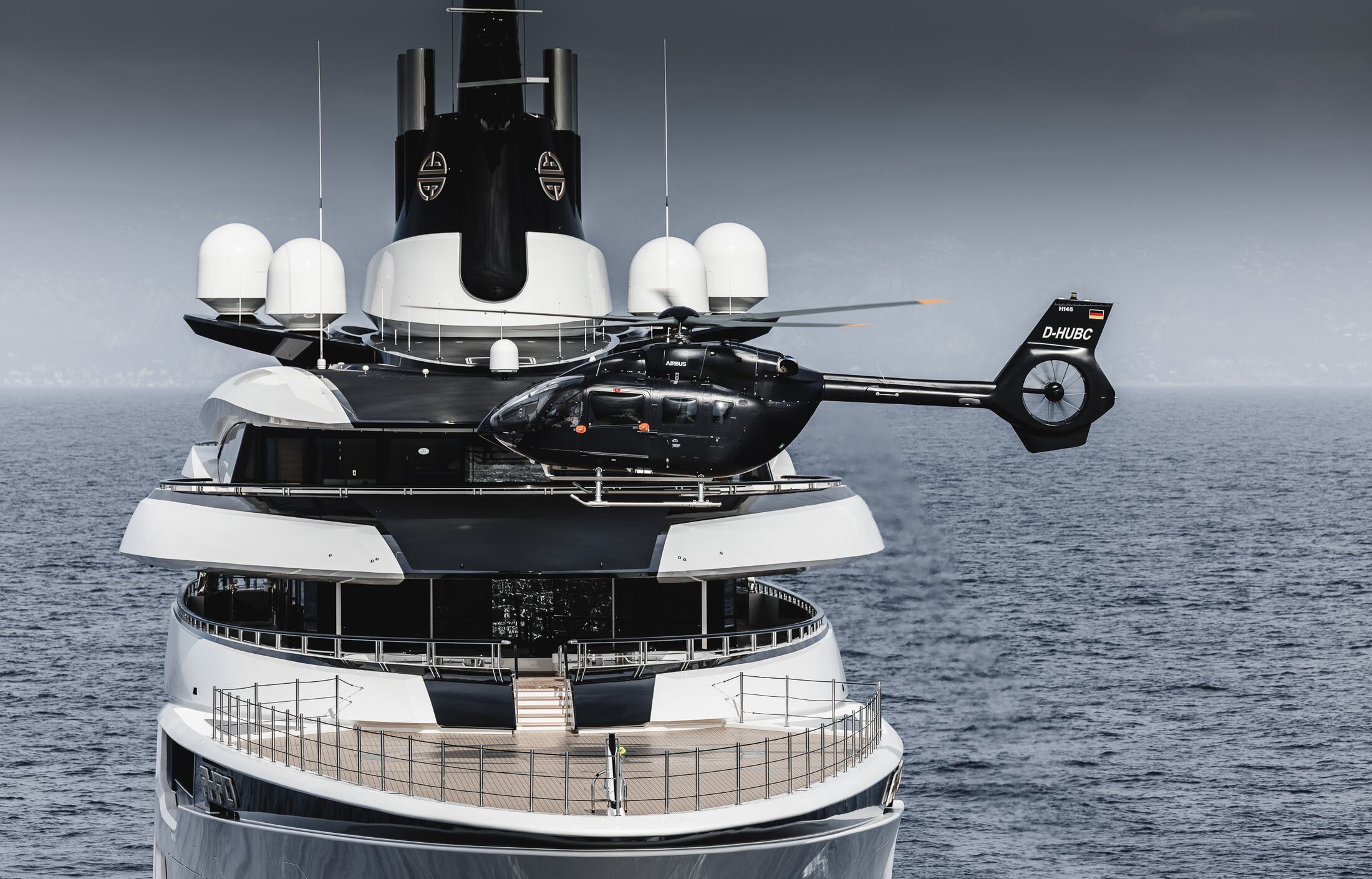 H145 hovering in front of a superyacht, both pilots visible